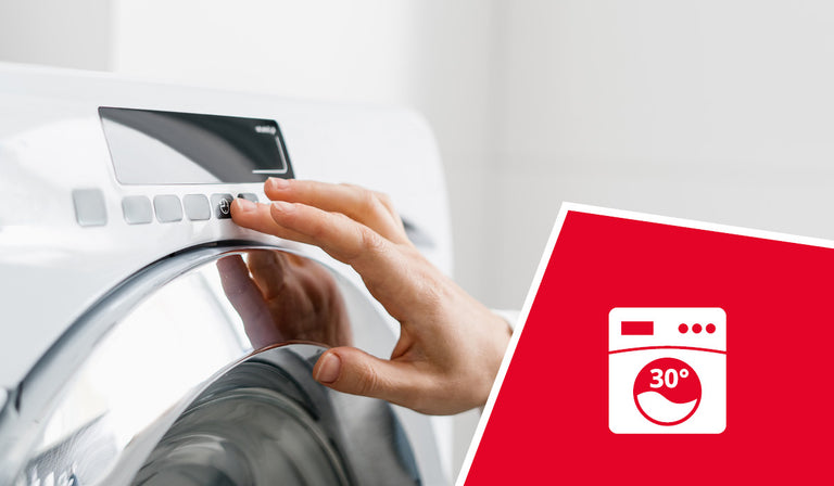 Une main réglant le bouton de commande d'une machine à laver blanche. Une icône rouge représente le symbole d'une machine à laver avec la mention « 30° », indiquant que le lavage en machine est possible à 30 °C.
