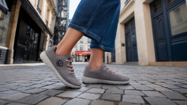 Une personne vêtue d'un jean et de baskets grises marche dans une rue pavée de la vieille ville.