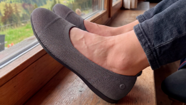 Gros plan sur les pieds d'une personne, posés sur un rebord de fenêtre en bois, dont le pantalon foncé est retroussé. 