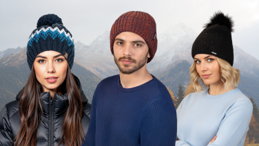 Trois jeunes gens portant des bonnets tricotés colorés devant un paysage montagneux enneigé