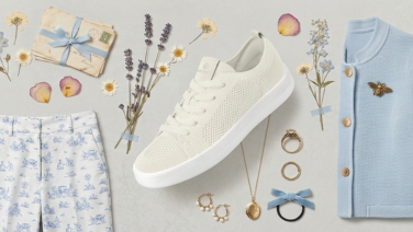 Flatlay d'une tenue printanière féminine dans les tons crème et bleu clair : pantalon à motifs, cardigan bleu clair, baskets Giesswein Merino couleur crème et accessoires tels qu'un collier, un bandeau pour les cheveux, décorés de fleurs séchées.