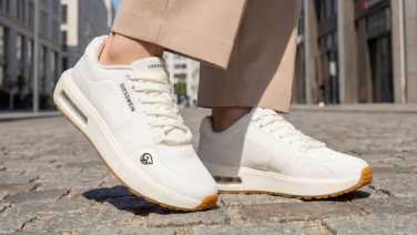 Gros plan sur des baskets Giesswein blanches avec semelle à chambre à air et semelle extérieure couleur miel sur des pavés.